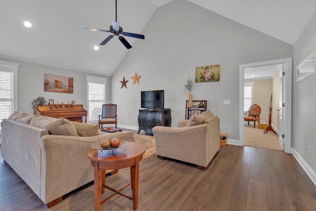 living room with dark wood-type flooring, ceiling fan, plenty of natural light, and a towering ceiling