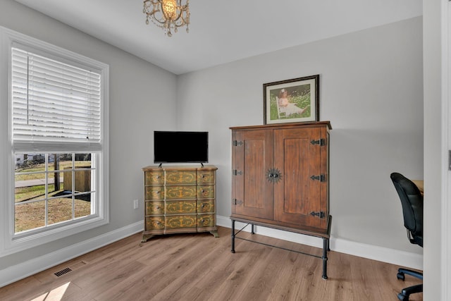 office area featuring an inviting chandelier and light wood-type flooring