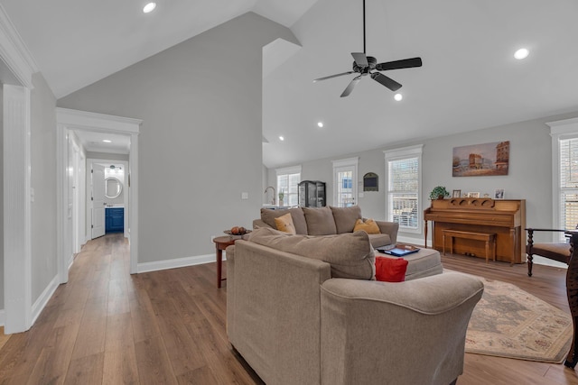 living room featuring light wood-type flooring, ceiling fan, and vaulted ceiling