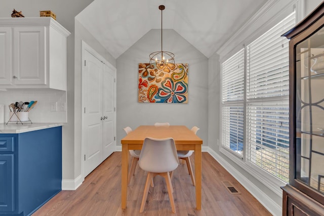 dining area featuring vaulted ceiling, an inviting chandelier, a wealth of natural light, and light hardwood / wood-style floors