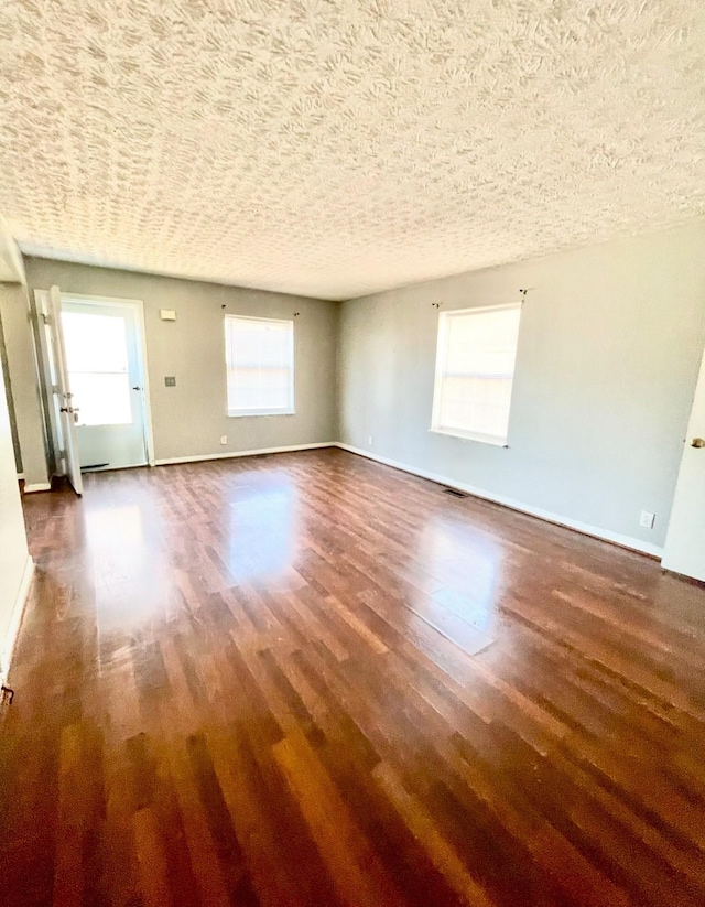 empty room featuring a textured ceiling and dark wood-type flooring