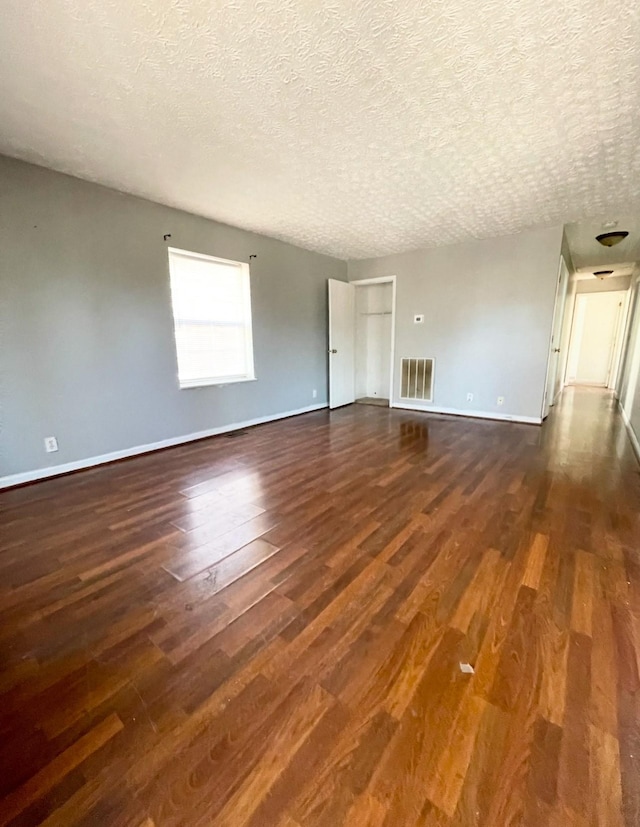 unfurnished living room with dark wood-type flooring and a textured ceiling