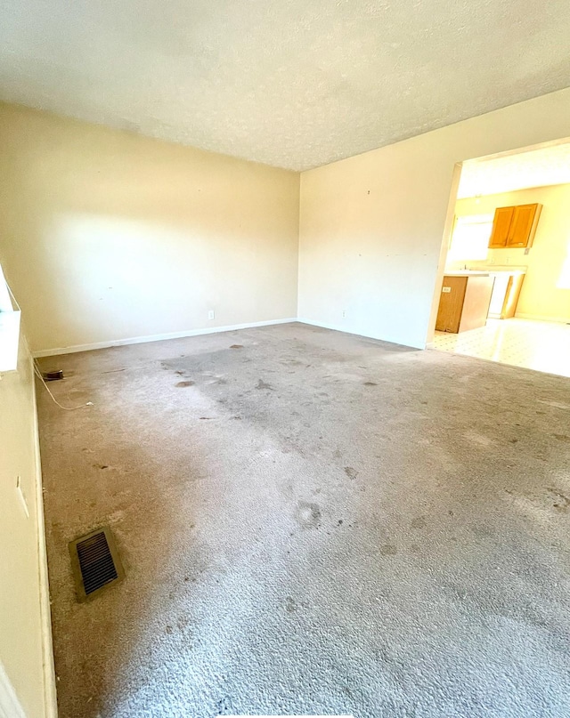 carpeted empty room featuring a textured ceiling