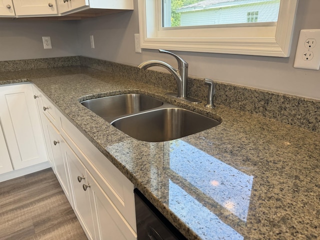 kitchen with white cabinetry, dark stone countertops, dark hardwood / wood-style floors, and sink