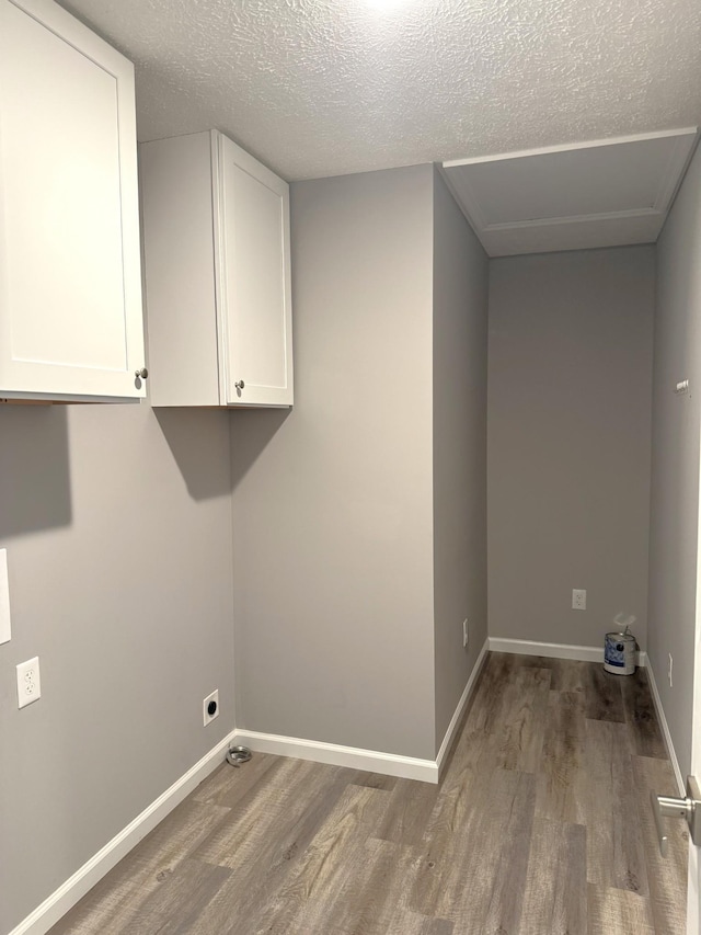 washroom with hardwood / wood-style flooring, cabinets, a textured ceiling, and hookup for an electric dryer