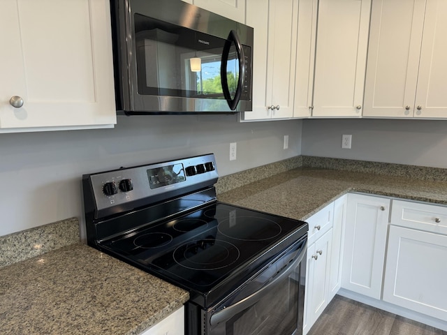 kitchen with wood-type flooring, white cabinets, dark stone counters, and range with electric cooktop