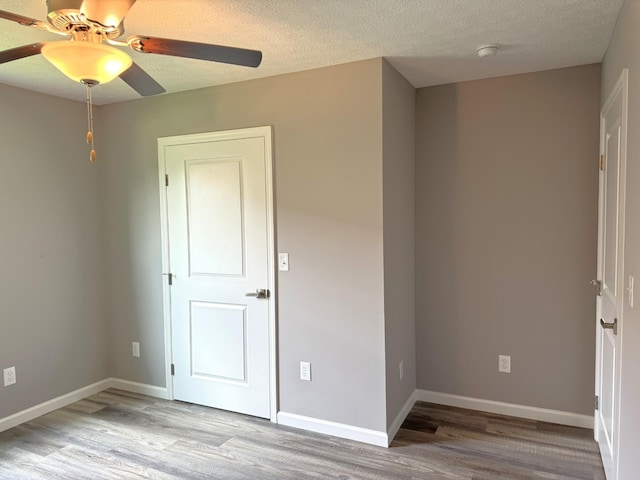 unfurnished bedroom with ceiling fan, a textured ceiling, and light hardwood / wood-style flooring