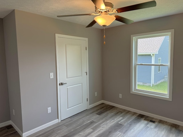 empty room with ceiling fan, a textured ceiling, and light hardwood / wood-style flooring