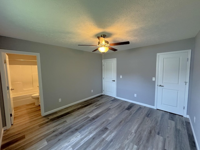 unfurnished bedroom with ceiling fan, wood-type flooring, ensuite bath, and a textured ceiling