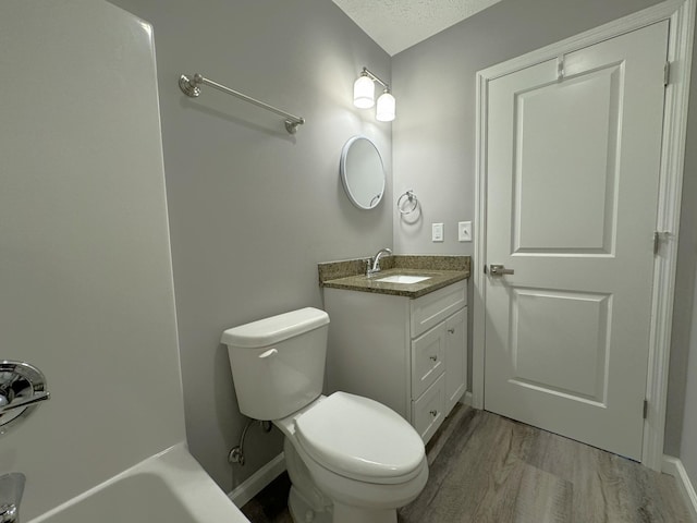 bathroom featuring toilet, a textured ceiling, wood-type flooring, and vanity