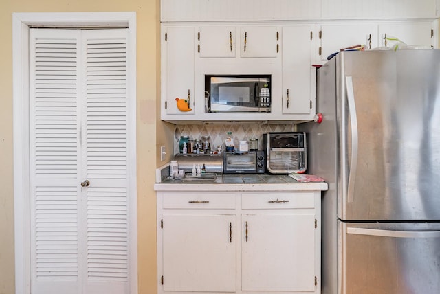 kitchen with white cabinets, stainless steel appliances, and backsplash