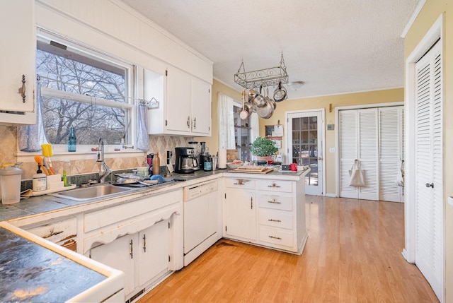 kitchen with a peninsula, a sink, white cabinetry, dishwasher, and light wood finished floors