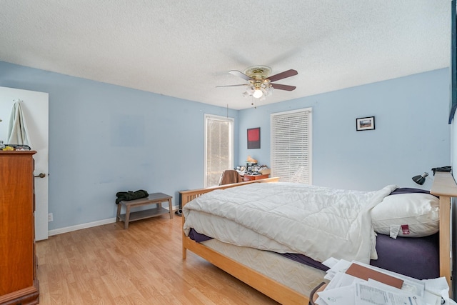 bedroom with baseboards, ceiling fan, a textured ceiling, and light wood finished floors