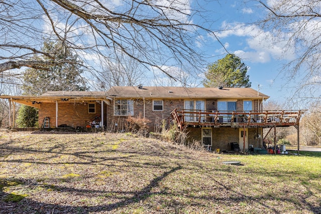 rear view of house featuring a wooden deck, a lawn, and brick siding