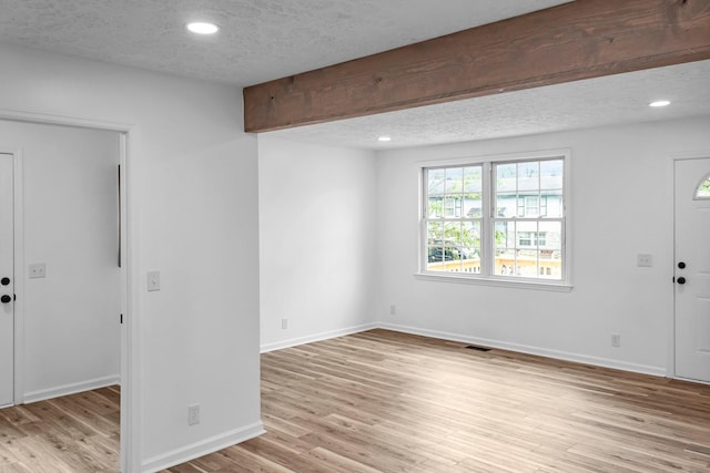 entryway featuring a textured ceiling, beam ceiling, and light wood-type flooring