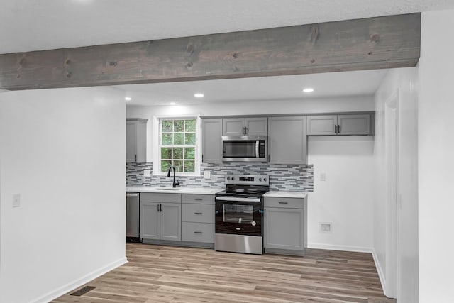 kitchen featuring light hardwood / wood-style floors, sink, appliances with stainless steel finishes, and gray cabinetry