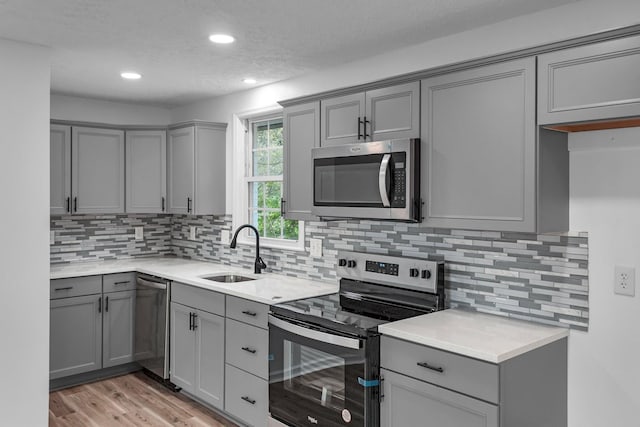 kitchen featuring sink, gray cabinetry, stainless steel appliances, and light hardwood / wood-style floors