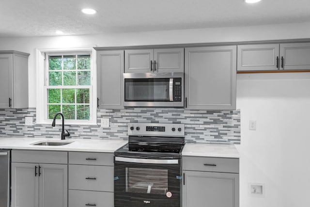 kitchen featuring gray cabinets, stainless steel appliances, tasteful backsplash, and sink