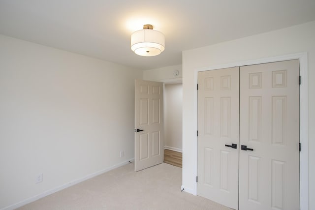 unfurnished bedroom with light colored carpet and a closet