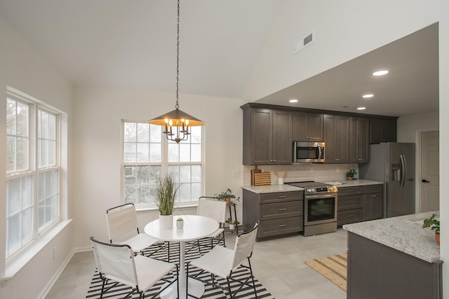 kitchen featuring lofted ceiling, stainless steel appliances, tasteful backsplash, a chandelier, and dark brown cabinets