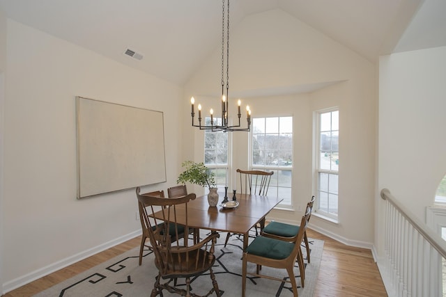 dining room featuring light wood-type flooring, a notable chandelier, and vaulted ceiling