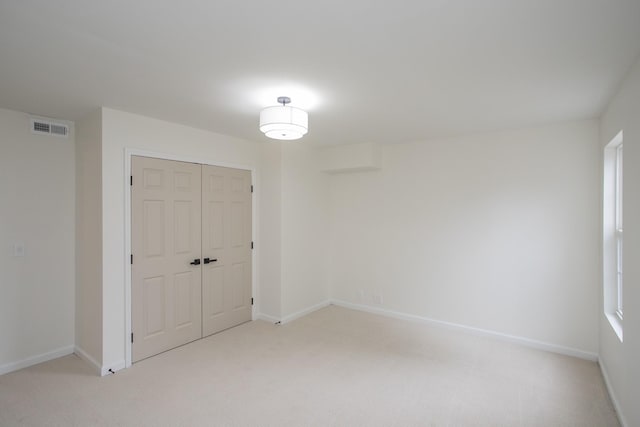 unfurnished bedroom with light colored carpet and a closet