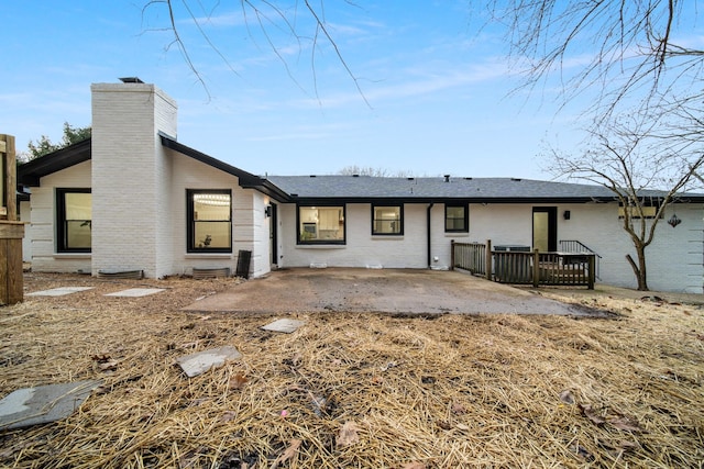 rear view of house featuring a patio, brick siding, and a chimney