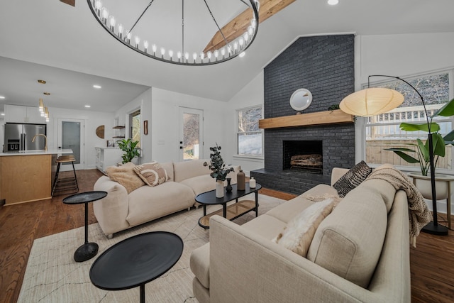 living area featuring a wealth of natural light, a fireplace, high vaulted ceiling, and wood finished floors