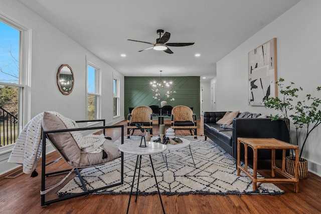 living area featuring ceiling fan with notable chandelier, an accent wall, wood finished floors, and recessed lighting