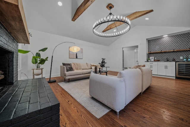 living room with a fireplace with raised hearth, wine cooler, a notable chandelier, dark wood-type flooring, and beamed ceiling