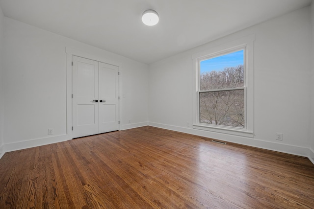 empty room with visible vents, baseboards, and wood finished floors