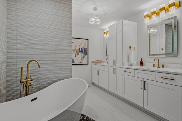 full bath with a sink, baseboards, a soaking tub, double vanity, and an inviting chandelier