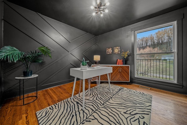 home office with a chandelier, visible vents, and wood finished floors