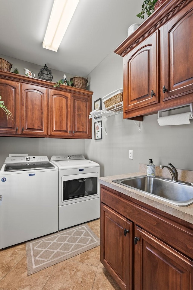 clothes washing area featuring sink, washing machine and dryer, light tile patterned flooring, and cabinets