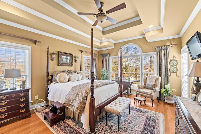 bedroom featuring ceiling fan, ornamental molding, light hardwood / wood-style floors, and a raised ceiling