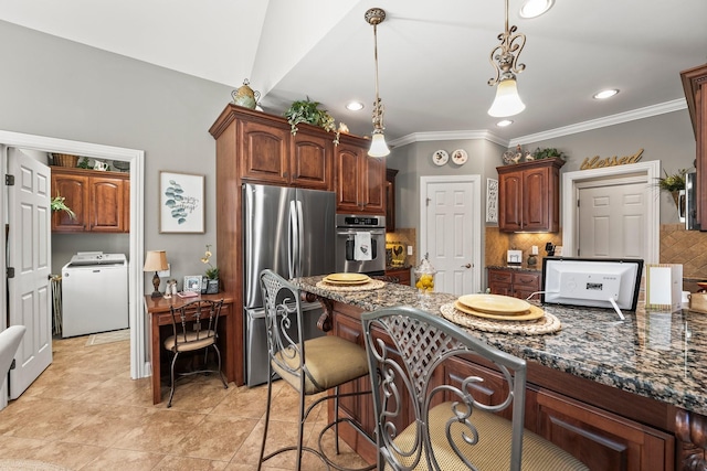 kitchen featuring washer / dryer, stainless steel appliances, backsplash, dark stone countertops, and hanging light fixtures