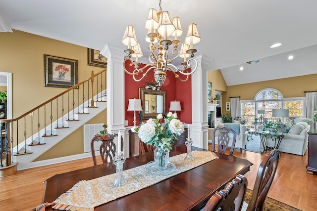 dining space with vaulted ceiling, a chandelier, wood-type flooring, and decorative columns