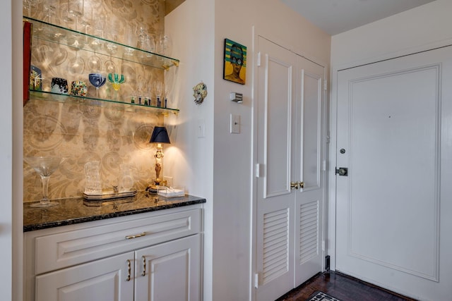 bar featuring white cabinetry, dark stone counters, and tasteful backsplash