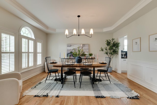 dining area featuring a tray ceiling, a chandelier, and light wood-type flooring