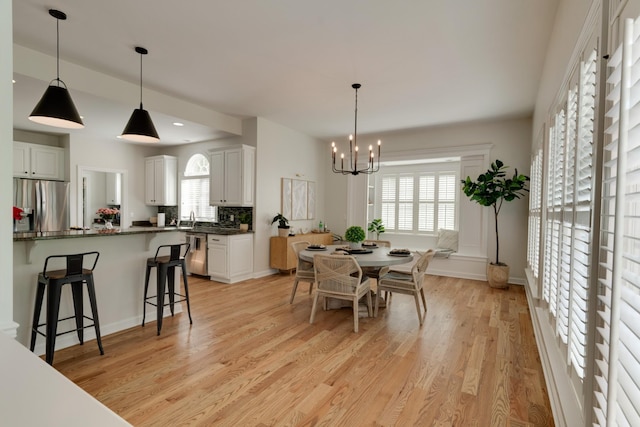 dining room featuring sink, light hardwood / wood-style flooring, and a chandelier