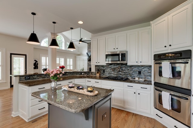 kitchen with kitchen peninsula, a kitchen island, stainless steel appliances, and white cabinetry