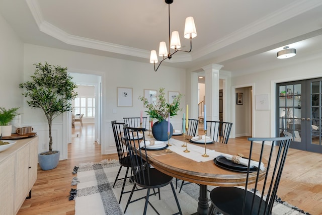 dining room with ornamental molding, a raised ceiling, light hardwood / wood-style floors, and french doors