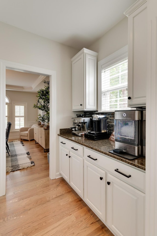 kitchen with white cabinetry, light hardwood / wood-style flooring, a wealth of natural light, and dark stone countertops