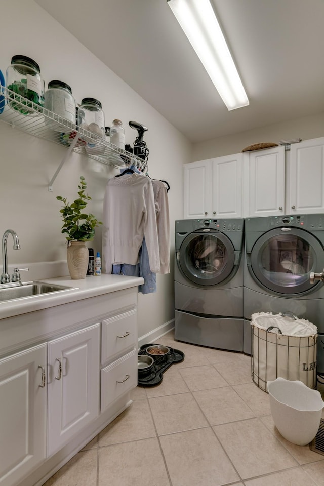 laundry area featuring cabinets, light tile patterned floors, sink, and washing machine and dryer