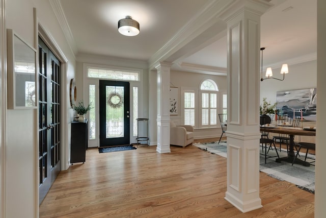 foyer with ornate columns, light hardwood / wood-style flooring, ornamental molding, and a chandelier