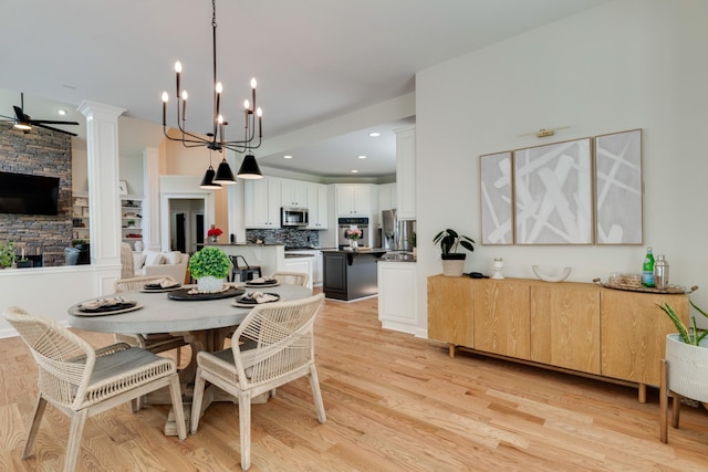 dining room featuring ceiling fan with notable chandelier and light hardwood / wood-style flooring