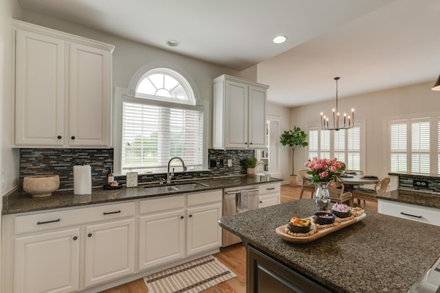 kitchen featuring dishwasher, sink, white cabinetry, and a center island