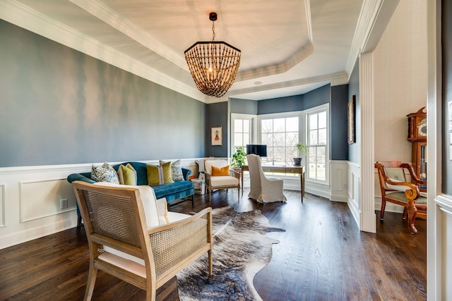 sitting room featuring a raised ceiling, dark wood-type flooring, an inviting chandelier, and ornamental molding