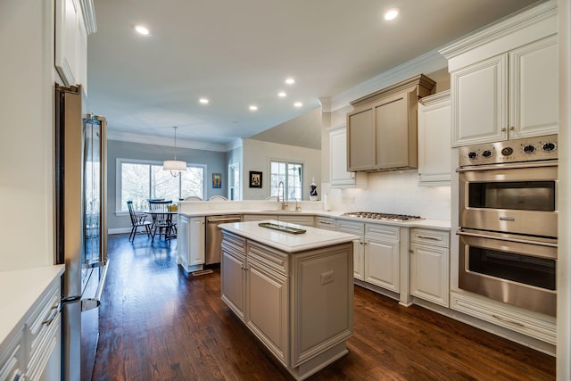 kitchen featuring pendant lighting, appliances with stainless steel finishes, a kitchen island, sink, and kitchen peninsula