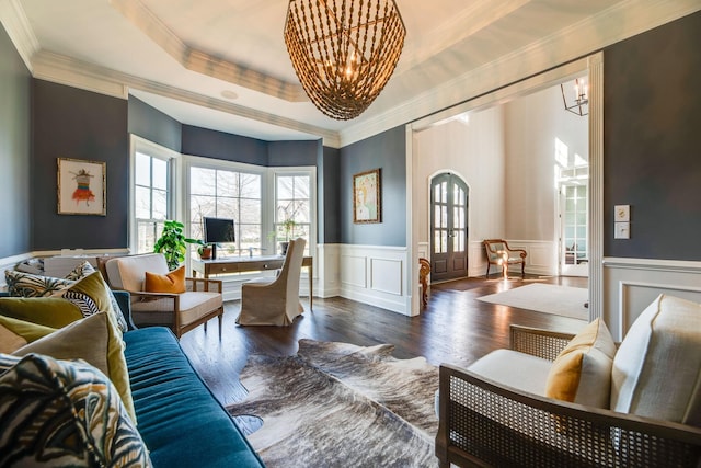 living area with plenty of natural light, dark hardwood / wood-style flooring, a tray ceiling, and a notable chandelier